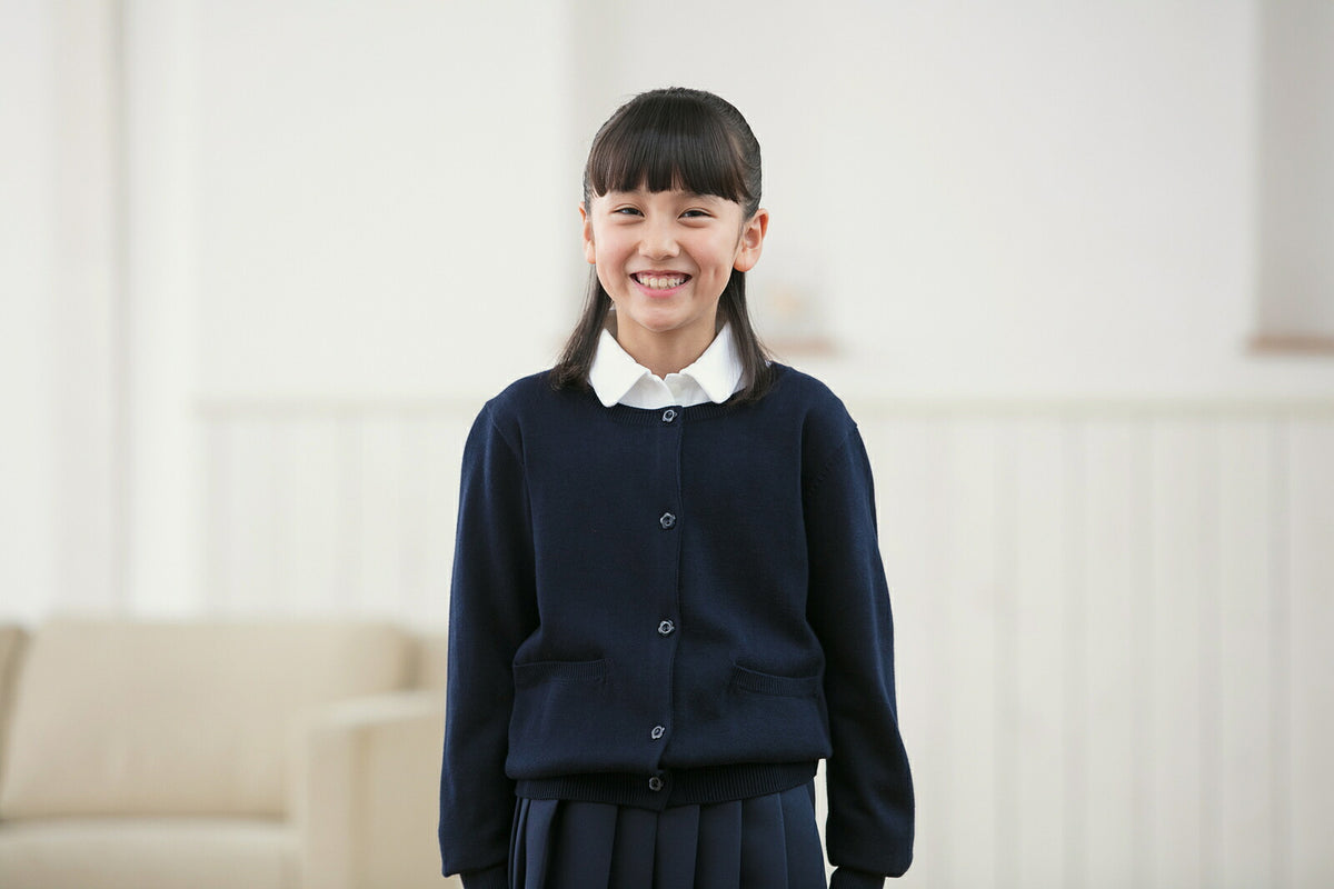 スクールカーディガンを着て笑顔で立つ女の子