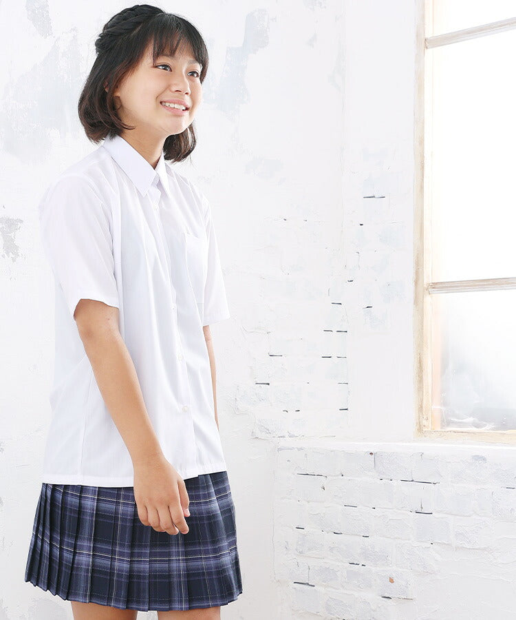 窓辺で斜め前を向いて立つ、シャツ姿の女の子